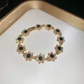 Detailed close-up of a vintage gold bracelet featuring sparkling blue flower charms and crystals - Bracelet-Gold-Blue