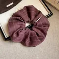 Gros plan d'un chouchou premium en tissu bordeaux avec rayures fines et chevrons. - Rouge