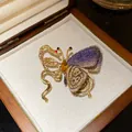 Macro view of vintage butterfly snake brooch with purple knit lace and amber crystal - Gold