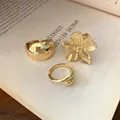 Close-up of gold-finish open rings including a flower design on an open book - Five Petal Flower Style / Set of 3 / Gold