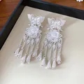 Vue détaillée en gros plan de boucles d'oreilles papillon fleur en argent avec glands - Argent