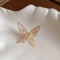 Close-up detail of an ethereal pink butterfly enamel ear clip with a golden metallic frame - Pink