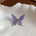 Detailed macro view of purple butterfly ear clip with gold-tone edges and elegant enamel finish - Purple