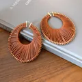 Bohemian woven brown leather hoop earrings with gold-tone hardware on a book backdrop - Large / Gold Brown