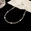Detailweergave van een minimalistische ketting met kleine witte parels en zilveren kralen - Parel Stijl / Zilver