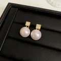 Macro detail of elegant gold-plated stud earrings with square CZ and lustrous pearls. - Square Style / Real Gold Plated / Gold