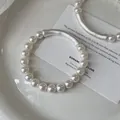 Vista dettagliata di eleganti bracciali di perle con tubi curvi in argento opaco - Bracciale / Bianco