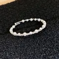 Detail eines eleganten offenen Armreifs mit glänzenden Perlen und funkelnden Straßsteinen - Feiner Strass Perlen Offener Stil (5#)