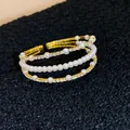 Nahaufnahme eines dreilagigen goldfarbenen Armreifs mit Perlen und funkelnden Strasssteinen - Dreilagiger Stacking Offener Stil (15#)