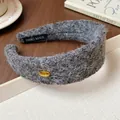 Close-up of a gray flocked wide headband featuring a gold Korea badge and fuzzy texture - Gray
