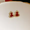 Close-up of elegant red enamel gourd stud earrings with sparkling zircon borders on a white plate - Silver Needle Gourd Style / Gold Red