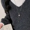 Primo piano di una collana con ciondolo a stella argento su un maglione grigio - Catena da Maglione Stella con Nappa (12#)