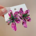 Close-up of pink marbled acetate flower earrings with green beaded stamens - Purple