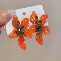 Close-up of vibrant orange flower earrings with detailed crystal stamen and green stems - Orange