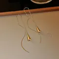Macro view of gold water-drop threader earrings with elegant curved lines and polished finish - Water Drop Tassel Ear Threader / Gold