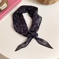 Détail d'un foulard en soie à imprimé paisley noir de style vintage français noué avec élégance - Bleu
