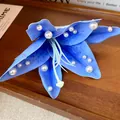 Macro view of blue fabric flower petals with delicate pearl accents hair clip - Blue