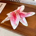 Detailed macro view of a pink fabric lily flower hair clip decorated with white pearls - Pink
