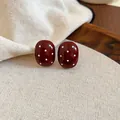 Elegant dark red oval stud earrings with white polka dots shown on linen fabric - Polka Dot Oval (42#)