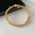 Macro detail of a twisted multi-strand gold choker necklace with clasp and chain. - Gold