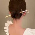 Detailed view of an elegant sword-shaped gold hairpin with rhinestone detail in a bun - Sword Style (HH3950) / 2# Hair Stick-Gold-White Handle