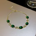 Close-up of elegant gold bracelet featuring oval emerald green zircons and floral accents. - 2. Gold Plated With Emeralds And Zircon. Bracelet.