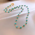Detail of gold-plated necklace featuring faceted turquoise beads on a silky background - Clavicle Necklace (HN6602) / Gold-Blue