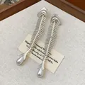 Macro detail of elegant silver-tone fishbone earrings featuring zirconia and pearl drops - White