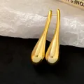 Detailed macro shot of sleek gold-toned water drop earrings featuring a smooth mirror finish - Teardrop / Gold