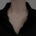Close-up of minimalist gold-plated stainless steel bean pendant necklace on model - Gold