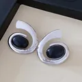 Macrodetail van zilverkleurige geometrische spiraaloorbellen met gepolijste zwarte stenen - Stud oorbellen / Zilver-Zwart