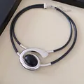 Detailopname van een dubbele halsketting met zilveren spiraal hanger en zwarte steen - Ketting / Zilver-Zwart