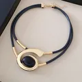 Detailopname van een geometrische spiraal choker ketting met goud metaal en steen - Ketting / Goud-Zwart
