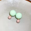 Nahaufnahme von pastellgrünen und rosa Doppelperlen-Ohrsteckern in einer Keramikschale - Doppelter Rundball (HE12707) / Grün