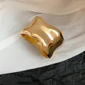 Primer plano de un brazalete de metal dorado irregular con superficie ondulada pulida - Anillo de Brazo Brillante Irregular (HB3720) / Dorado