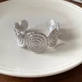 Silver textured spiral cuff bracelet with artistic pleated design on white plate - Silver