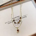 Detailed close-up of a vintage tiger eye beaded necklace with an elegant golden pendant - Gold Brown