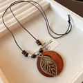 Detail view of retro ethnic style long necklace with hollowed leaf and wooden pendant. - Necklace-Coffee