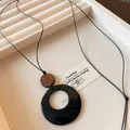 Detail shot of an ethnic style long necklace with a hollow round black pendant and wooden accent - Necklace-Black-Coffee