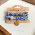 Detailed view of multi-layer blue beaded bracelets featuring a golden heart charm - Four-Piece Set / Dark Blue