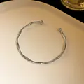 Elegant twisted silver-finish open bangle bracelet featuring hammered texture and bead ends - Silver