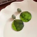 Gros plan de boucles d'oreilles pendantes en résine vert forêt sur une assiette - 2# (HE18974-3) / Vert