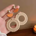 Detailed view of bohemian woven rattan earrings featuring orange geometric wooden accents - Woven Round Style (HE19002)