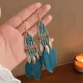Detailed view of bohemian teal feather tassel earrings with gold tribal accents - Feather Tassel Hook (HE20859-1)