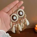 Close-up detail of Bohemian tassel earrings featuring golden leaves and soft fabric fringes. - Enamel-Look Fabric Tassel (HE20859-1)