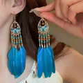 Close-up of bohemian blue feather earrings with intricate gold filigree and beads - Hollow Petal Feather Tassel (HE20859-1)