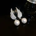Close-up of elegant wing-shaped earrings with rhinestones and white pearls - Earrings (Silver)