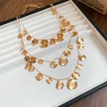 Detailed close-up view of triple-layered gold necklace with hammered round metal disc charms - Three-Piece Set / Gold