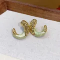 Close-up view of elegant gold wrinkled C-shape earrings with light green enamel drip finish - Gold-Green