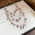 Detailed view of silver triple-layered necklace with textured crumpled circular pendants. - Three-Piece Set / Silver